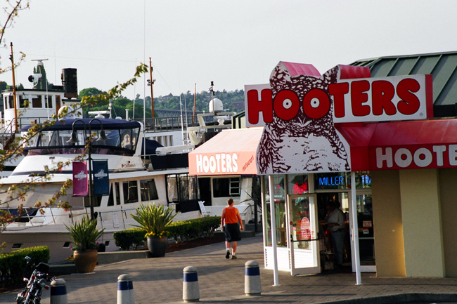 <b>Hooters</b><br />
Seattle fancies itself a highbrow town, with a citizenry more likely to read Proust over a glass of Bordeaux than ogle breasts over a plate of hot wings. So when the first Hooters in Seattle opened here, on the southern end of Lake Union, about a decade ago, it caused something of a kerfuffle, with many bemoaning the coarsening of our erudite, Pacific Northwest culture. The upside to this is that everyone knows where the Hooters is, which makes it easy for me to give people directions to my place of business just up the road.<br /><br />
<b>Me:</b> From I-5 take the Mercer Street exit. As soon as the off ramp ends, you need to rapidly change lanes twice, to get over into the rightmost lane, and then go around the corner, at which point Mercer will become Fairview Avenue North, and then stay in the right-hand lane and take another right—it’s really more of a curve than a turn—onto Fairview Avenue East. Did you follow all that?<br /><br />
<b>Them:</b> Not really.<br /><br />
<b>Me:</b> OK, so you’re taking the Mercer Street exit, right? And when you… oh, forget it. You know where Hooters is, right?<br /><br />
<b>Them:</b> Uhh, well, I’m not really…<br /><br />
<b>Me:</b> Shut up, I know you do. Go like you’re going to Hooters but then go half a mile farther.<br /><br />
<b>Them:</b> Got it.<br /><br />
Mileage: 0.5 of 6.0